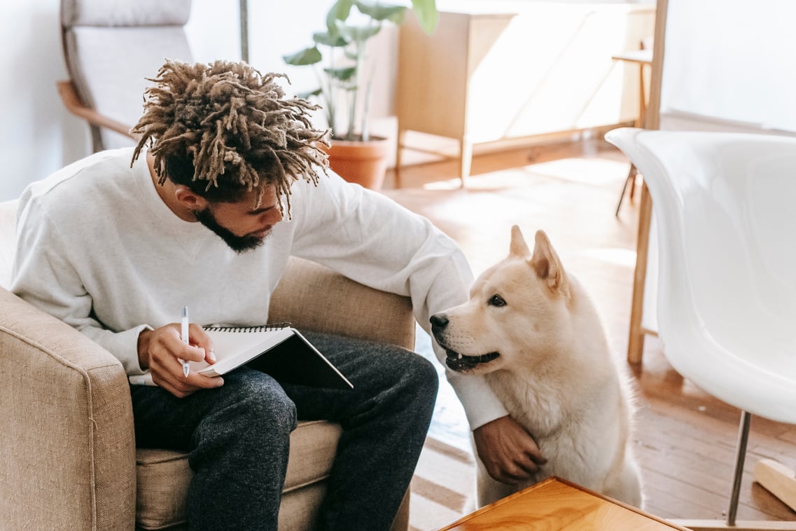 Black man with notebook petting dog